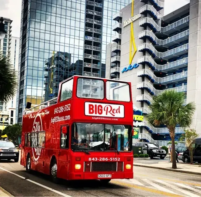 A red double decker bus is driving down a city street