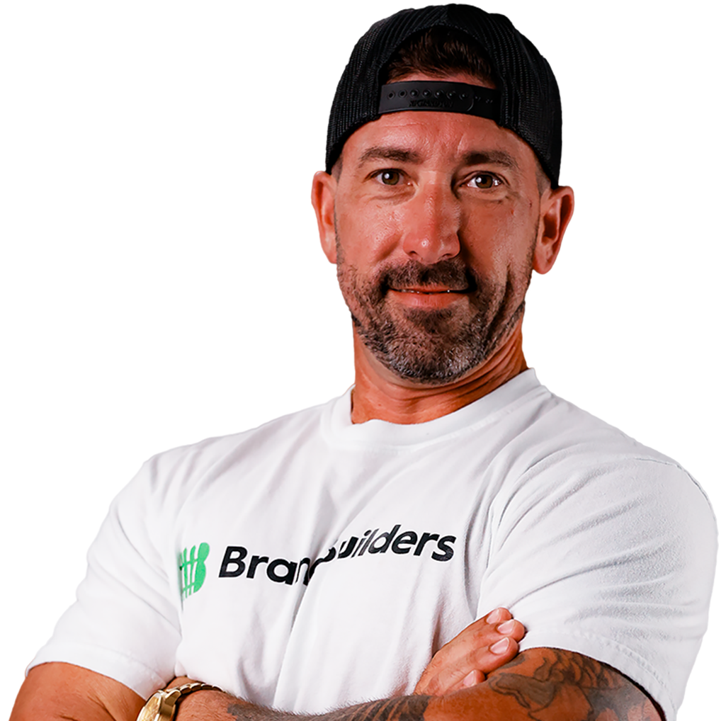 Man in a white Bravado shirt and black cap, arms crossed against a white background.