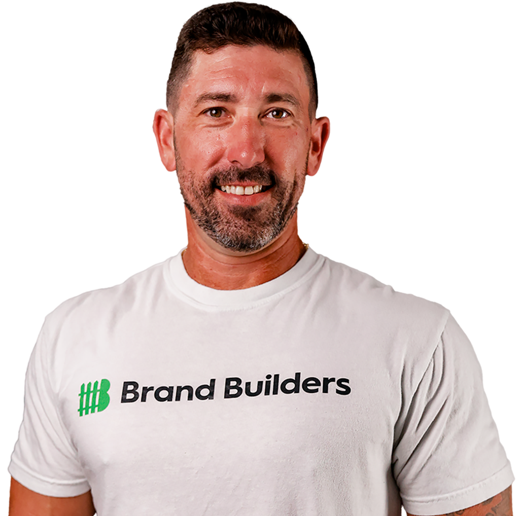 Man in a white Brand Builders T-shirt against a white background, smiling.