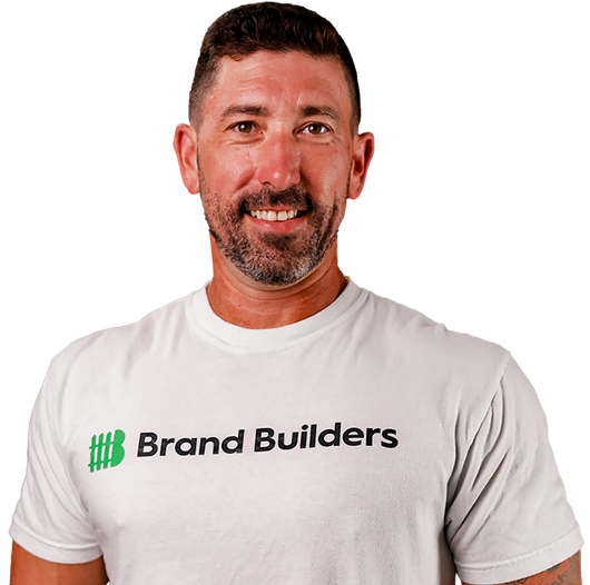Man in a white Brand Builders T-shirt against a white background, smiling.