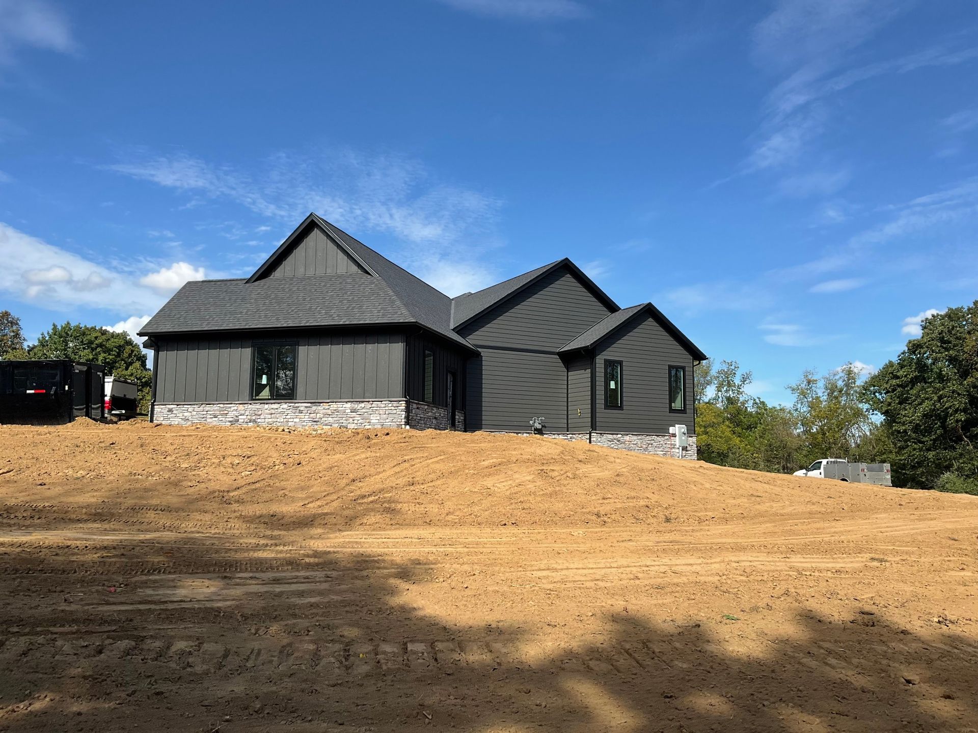 New black house under construction on a dirt lot under a blue sky