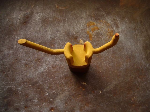 Un ugello spray in plastica gialla a due punte, appoggiato su una superficie scura e ruvida.