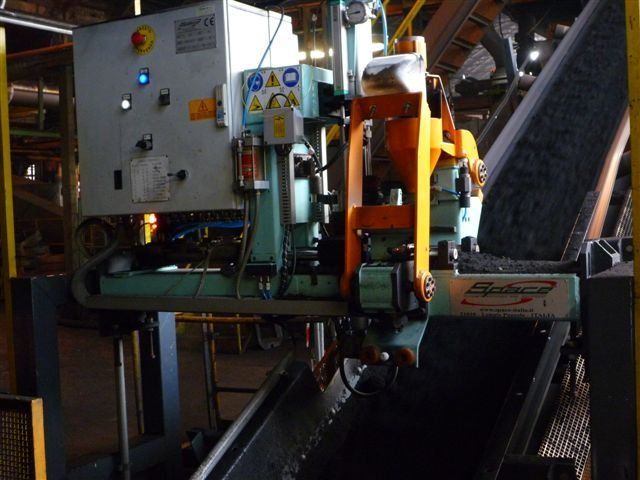 Macchinari industriali montati sopra un nastro trasportatore in un ambiente di fabbrica, con quadro di controllo e componenti meccanici.