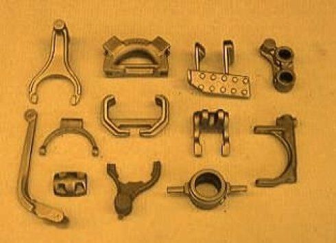 Una collezione di vari componenti meccanici e ingranaggi in metallo color bronzo, disposti su una superficie piana.