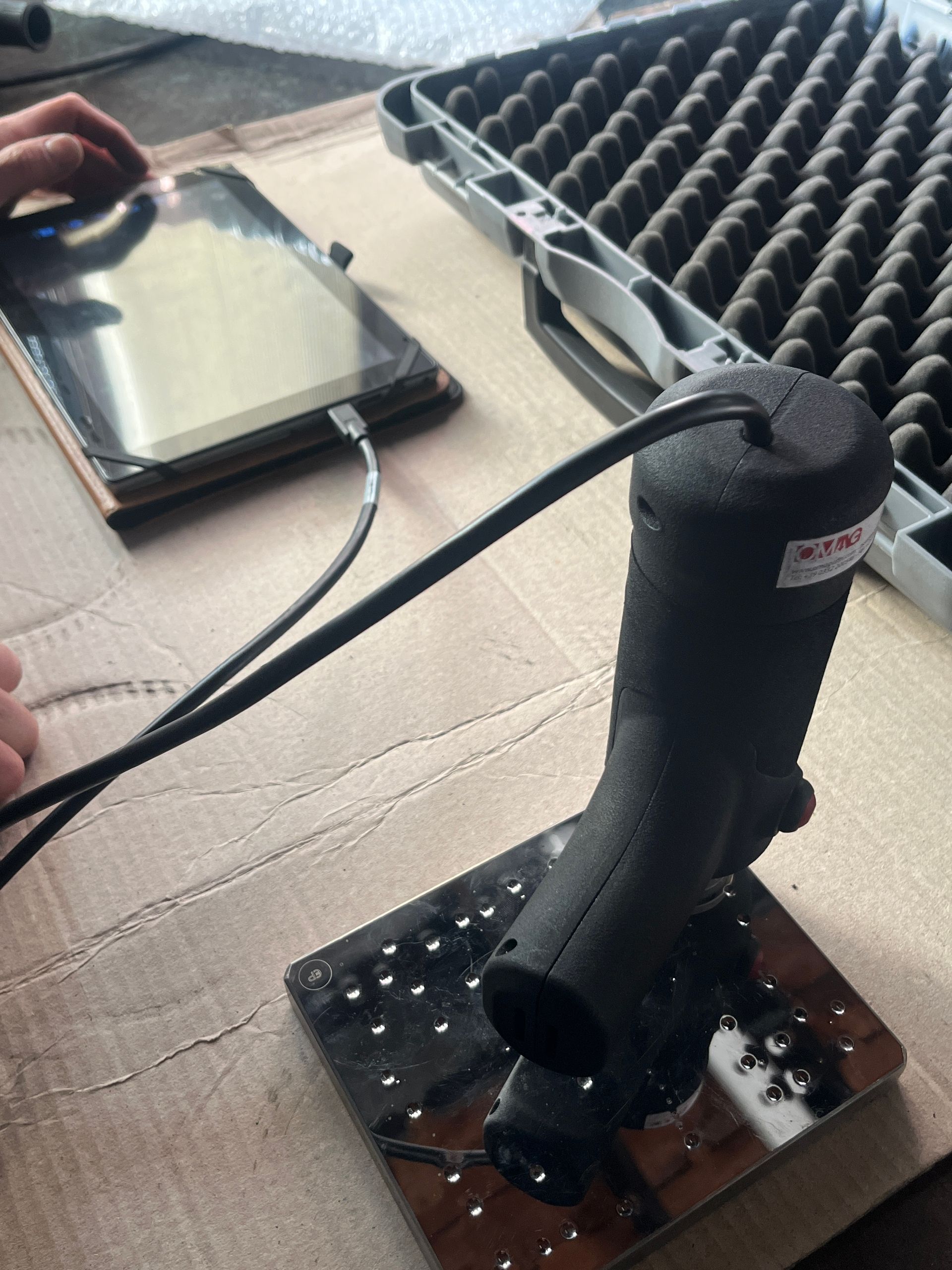 Uno scanner portatile collegato a un tablet è appoggiato su una superficie accanto a una custodia protettiva aperta.