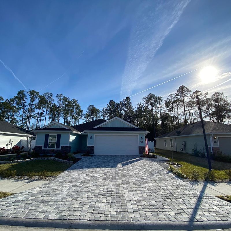 A house with a brick driveway in front of it.