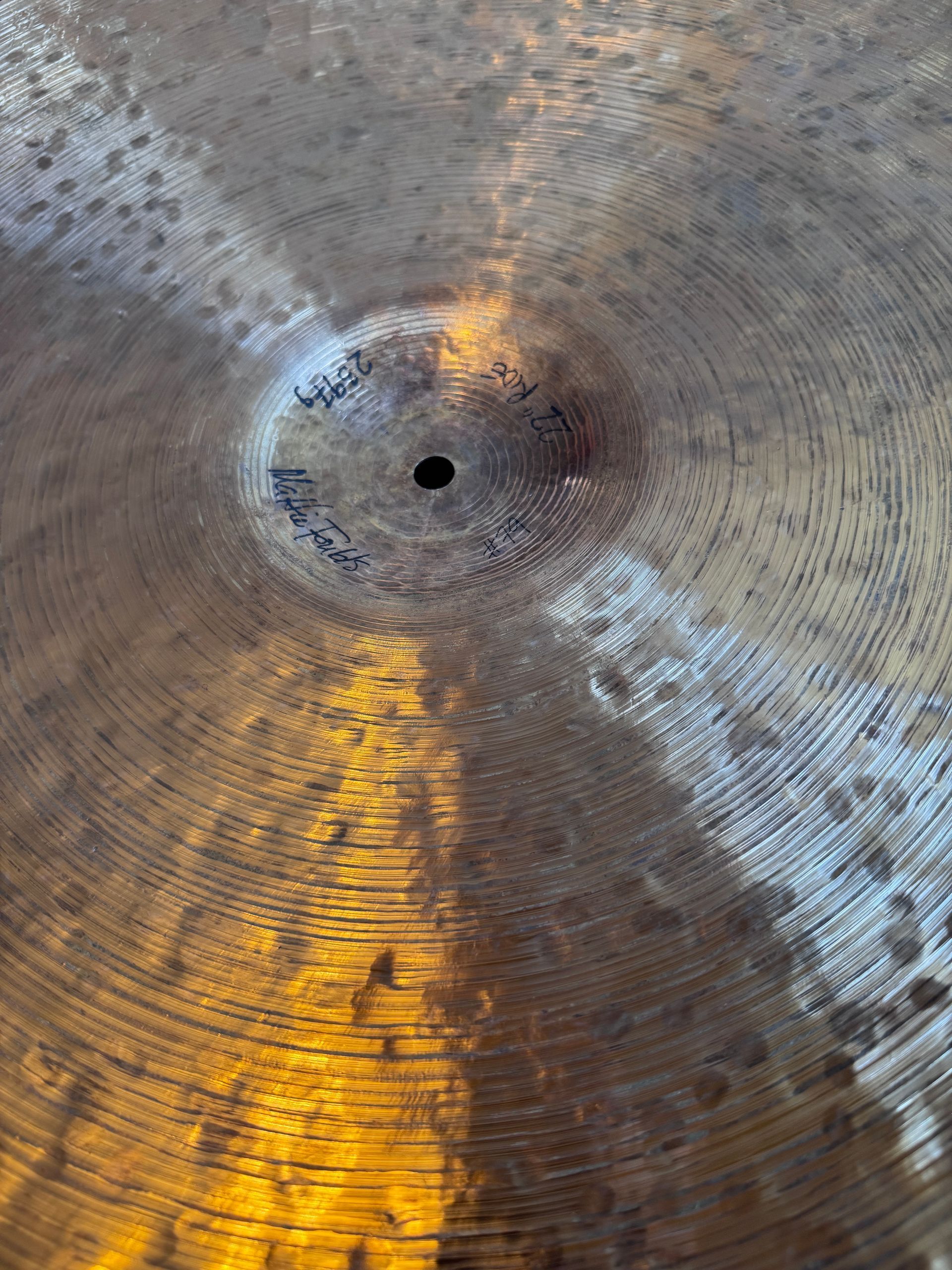 Close-up of a weathered metal surface with concentric grooves and a central hole, lit by warm yellow reflections