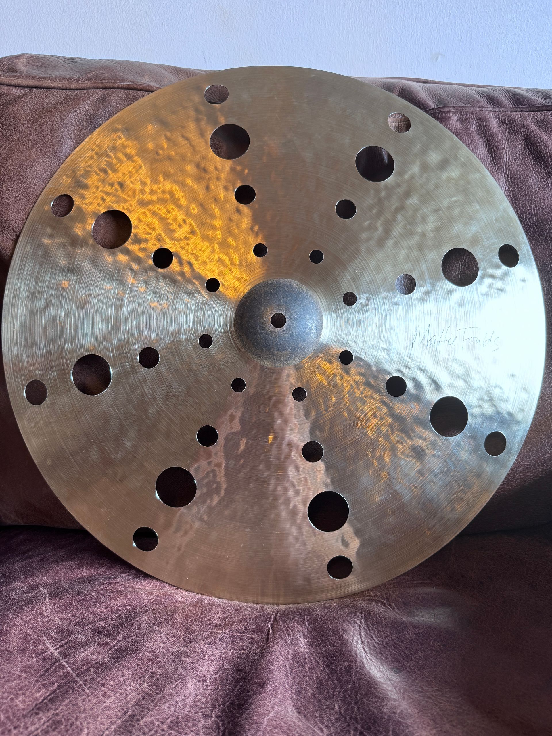 Metal lathe faceplate with multiple holes and central hub, resting on a purple cloth background