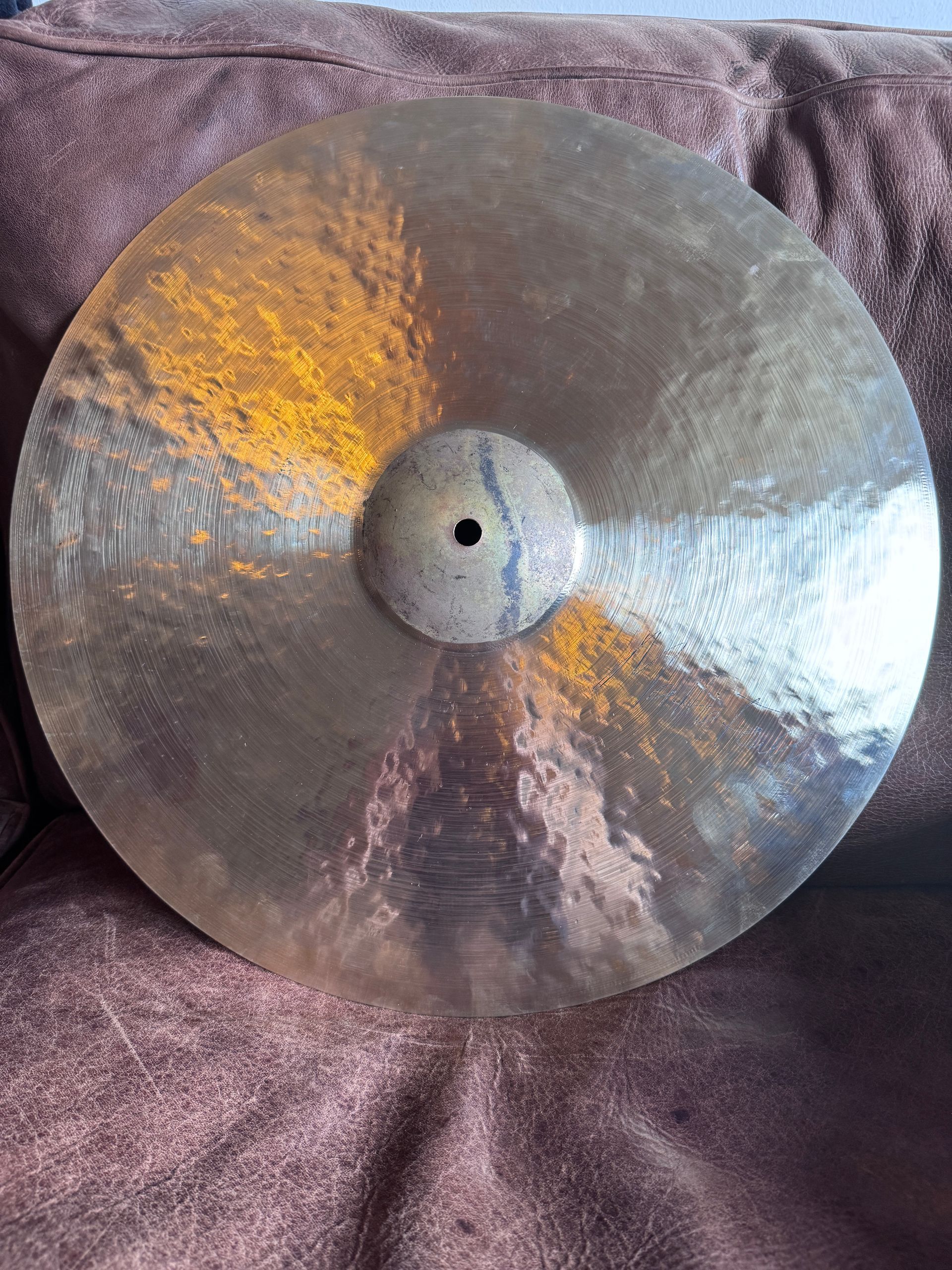 Large reflective metal disc with a center hole resting on a purple textured fabric.