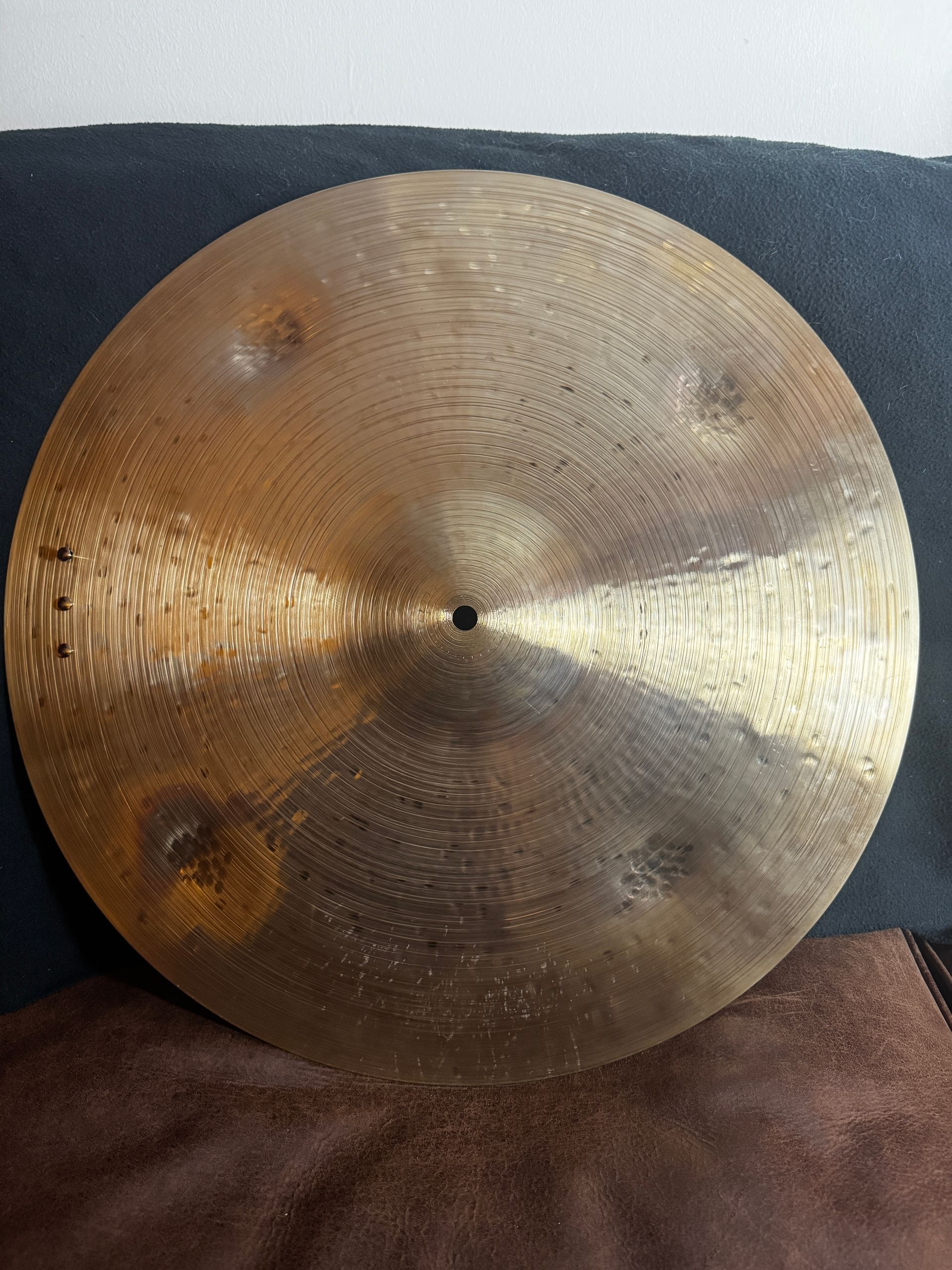 Brass cymbal resting on a dark surface, with a dark center and textured hammered finish