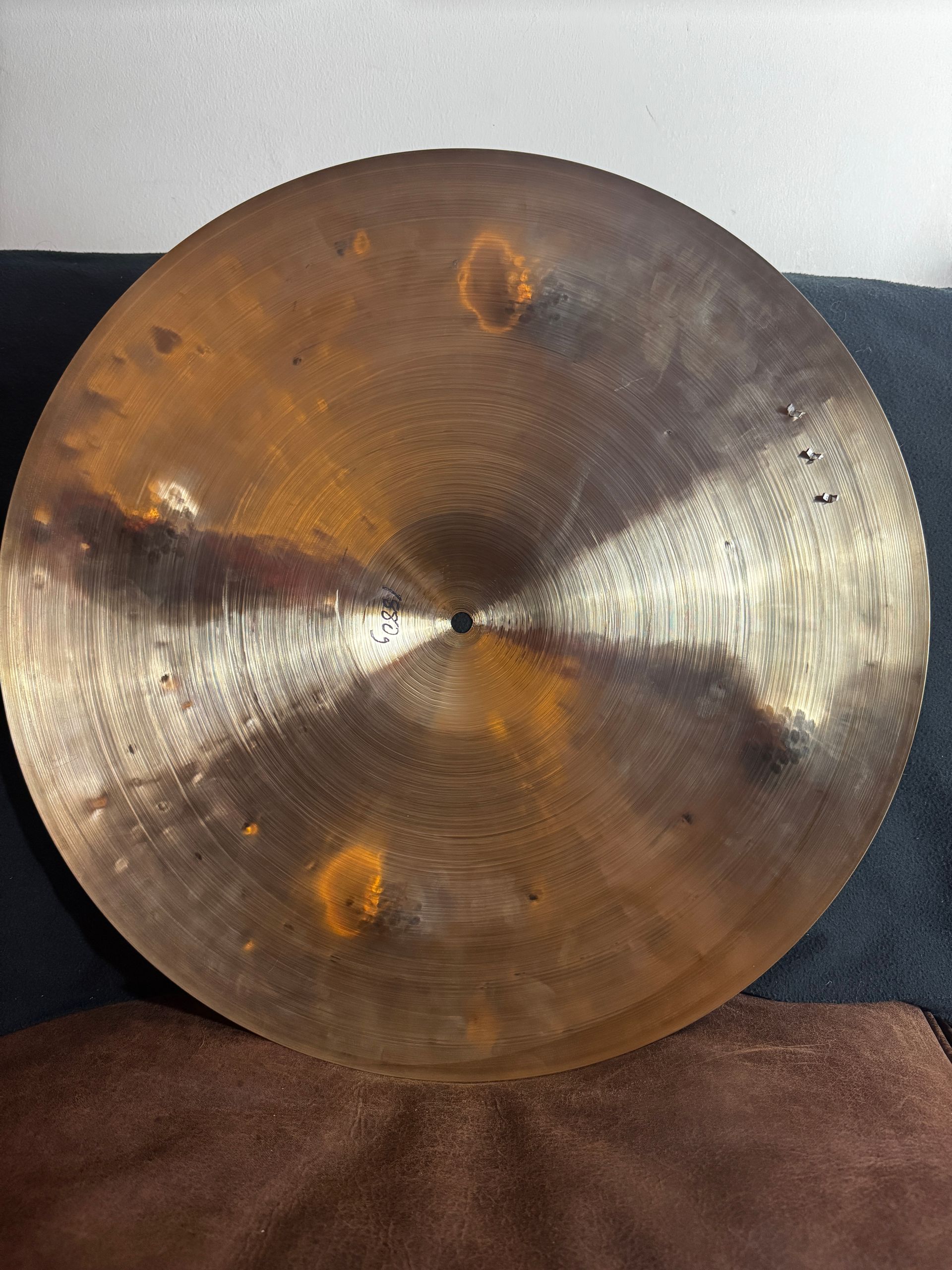 Brass cymbal resting on a dark surface, with a dark center and textured hammered finish