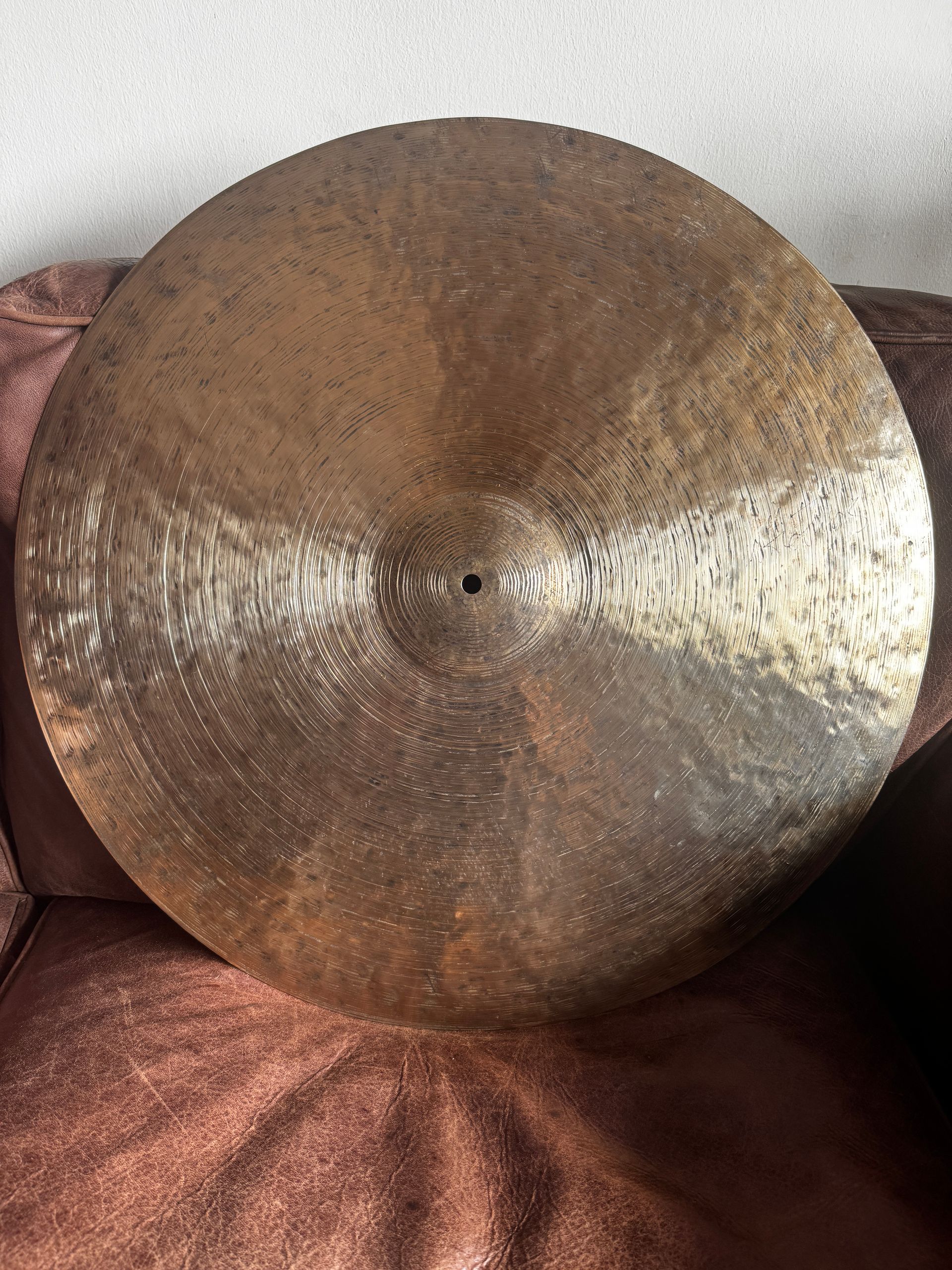 Close-up of a round bronze gong-like disc resting on a red textured fabric surface.