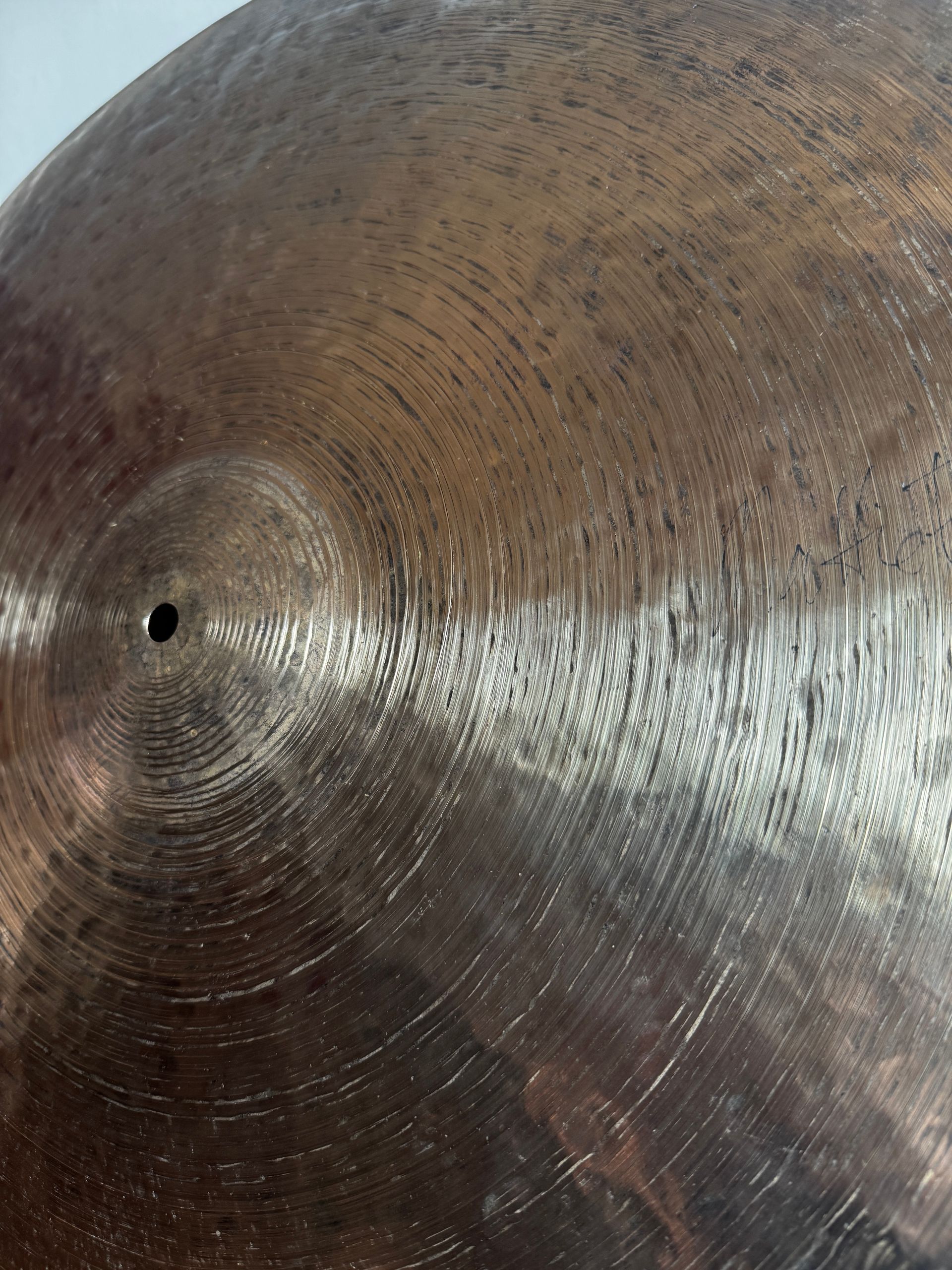 Close-up of a round bronze gong-like disc resting on a red textured fabric surface.