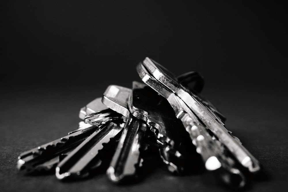 A small cluster of silver keys on a dark surface, reflecting light.