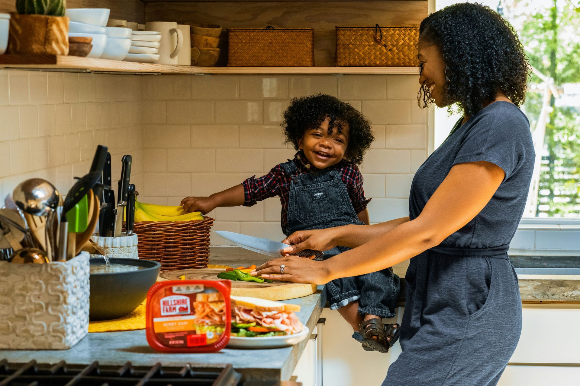 Woman and child in kitchen preparing a sandwich together.