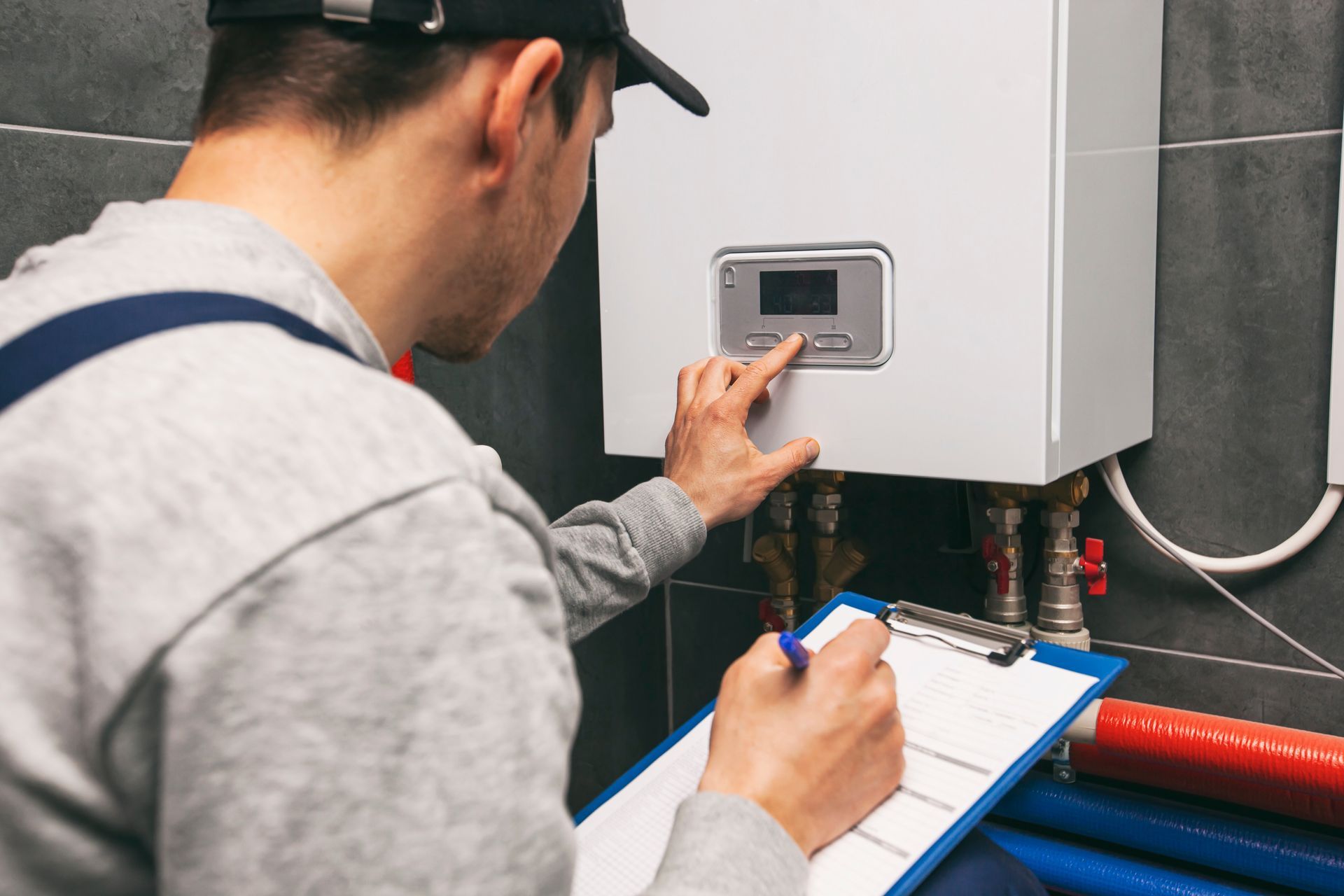 Technician inspecting a boiler control panel with a clipboard in a utility room