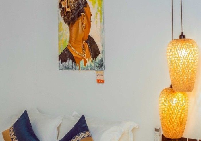 There is a painting of a woman on the wall above the bed.