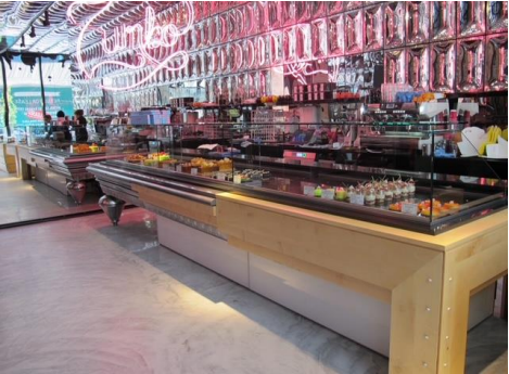 Une boulangerie lumineuse avec des vitrines en verre remplies de pâtisseries et de friandises, un éclairage rose néon.