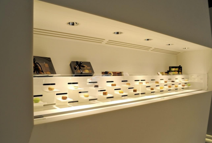 Vitrine de petits desserts sur assiettes individuelles. Intérieur blanc, éclairage zénithal.