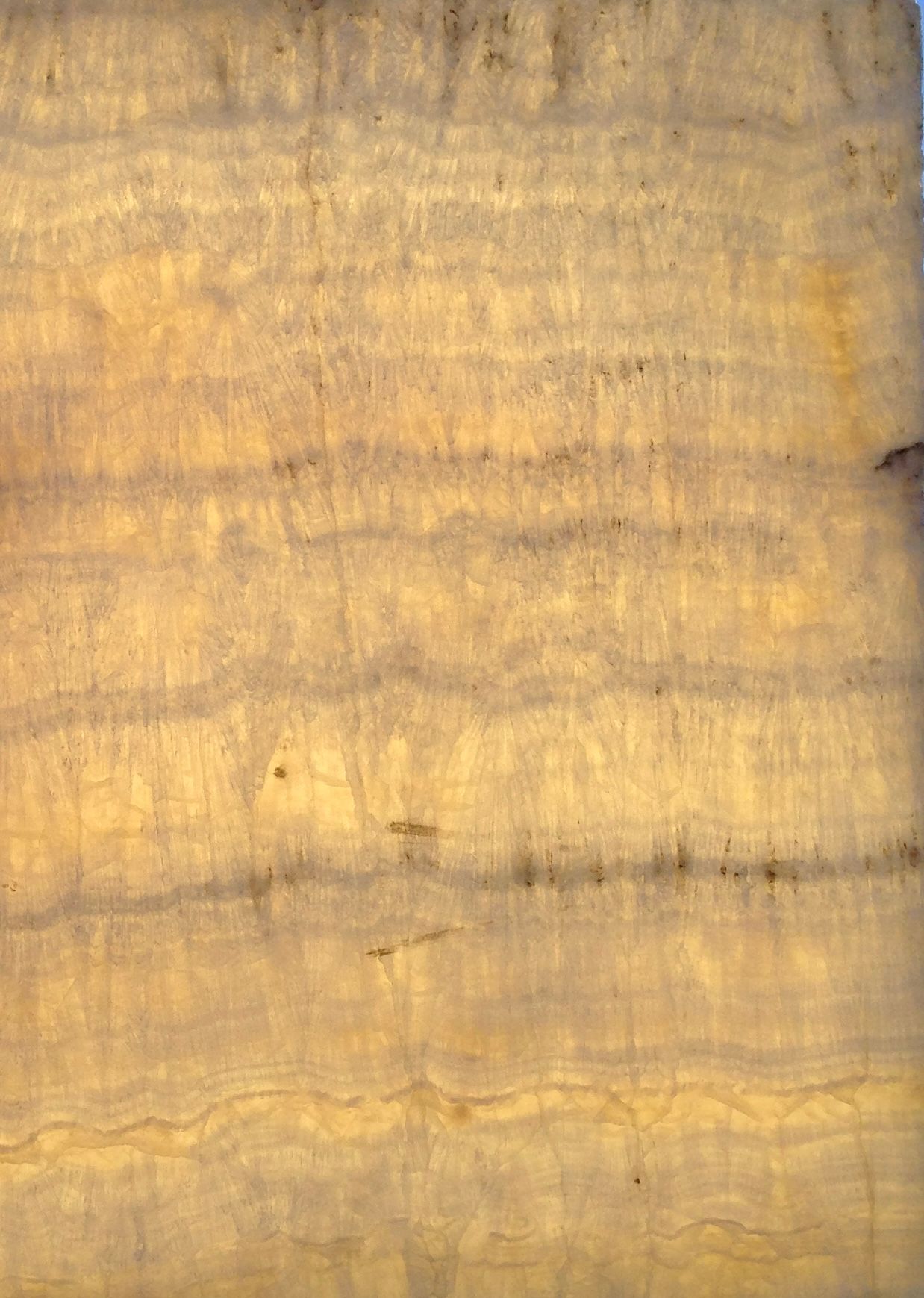 Surface de pierre stratifiée jaune et grise, peut-être en onyx, avec des bandes horizontales et des variations subtiles.