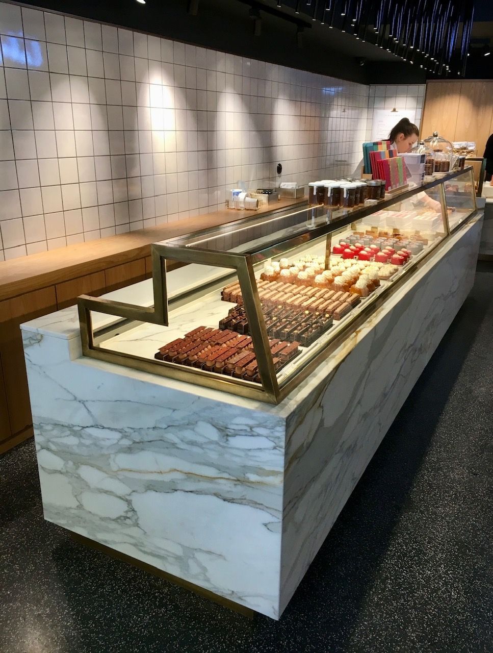 Présentoir à pâtisseries avec socle en marbre. Des gourmandises sont exposées à l'intérieur.