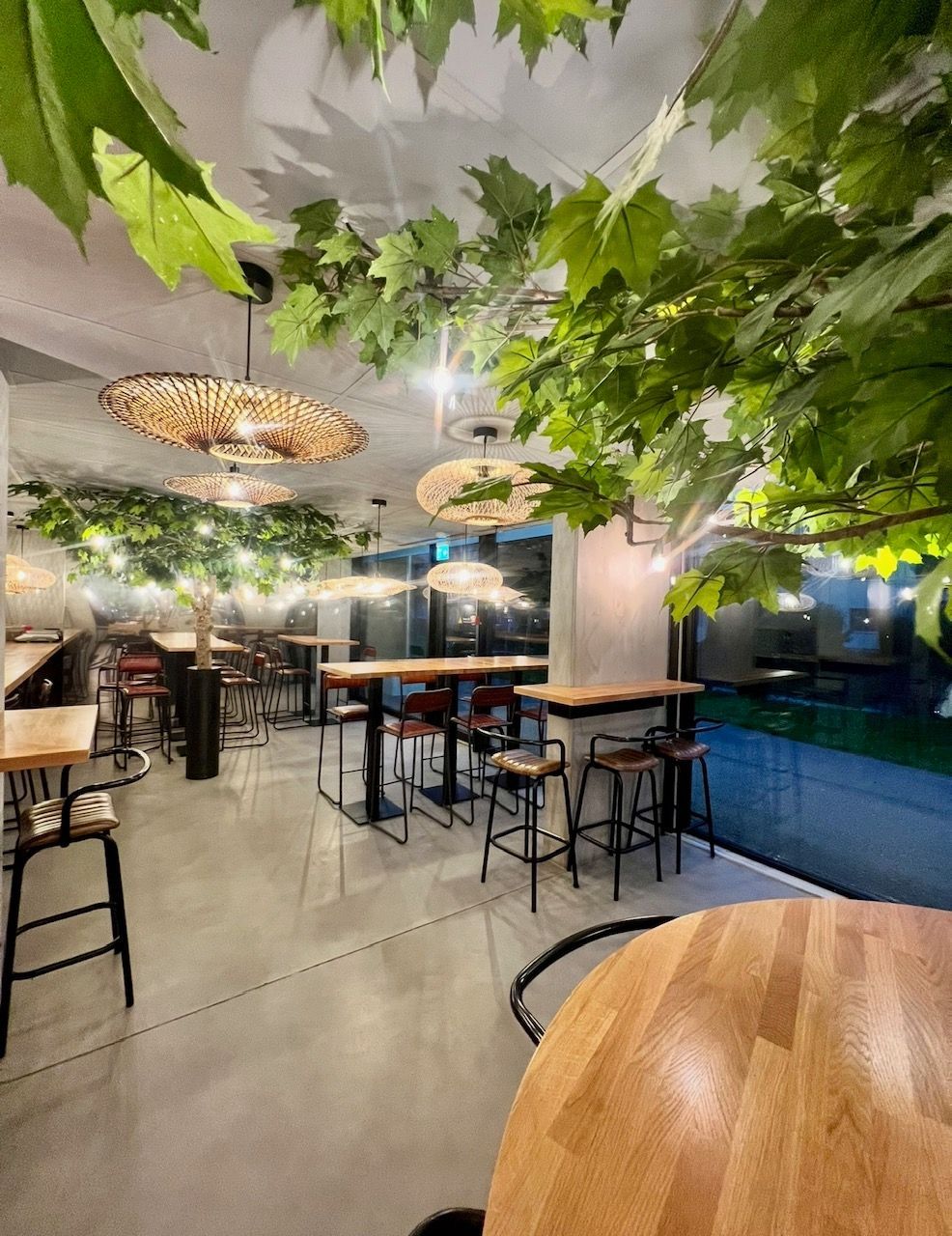 Intérieur du restaurant : tables avec tabourets de bar sous un plafond décoratif en feuilles.