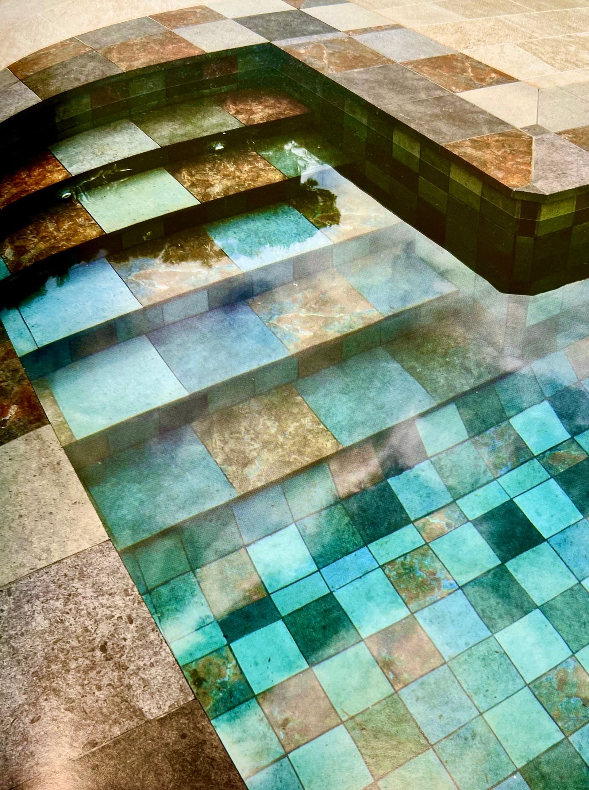 Piscine avec motif en damier carrelé, marches et eau claire.