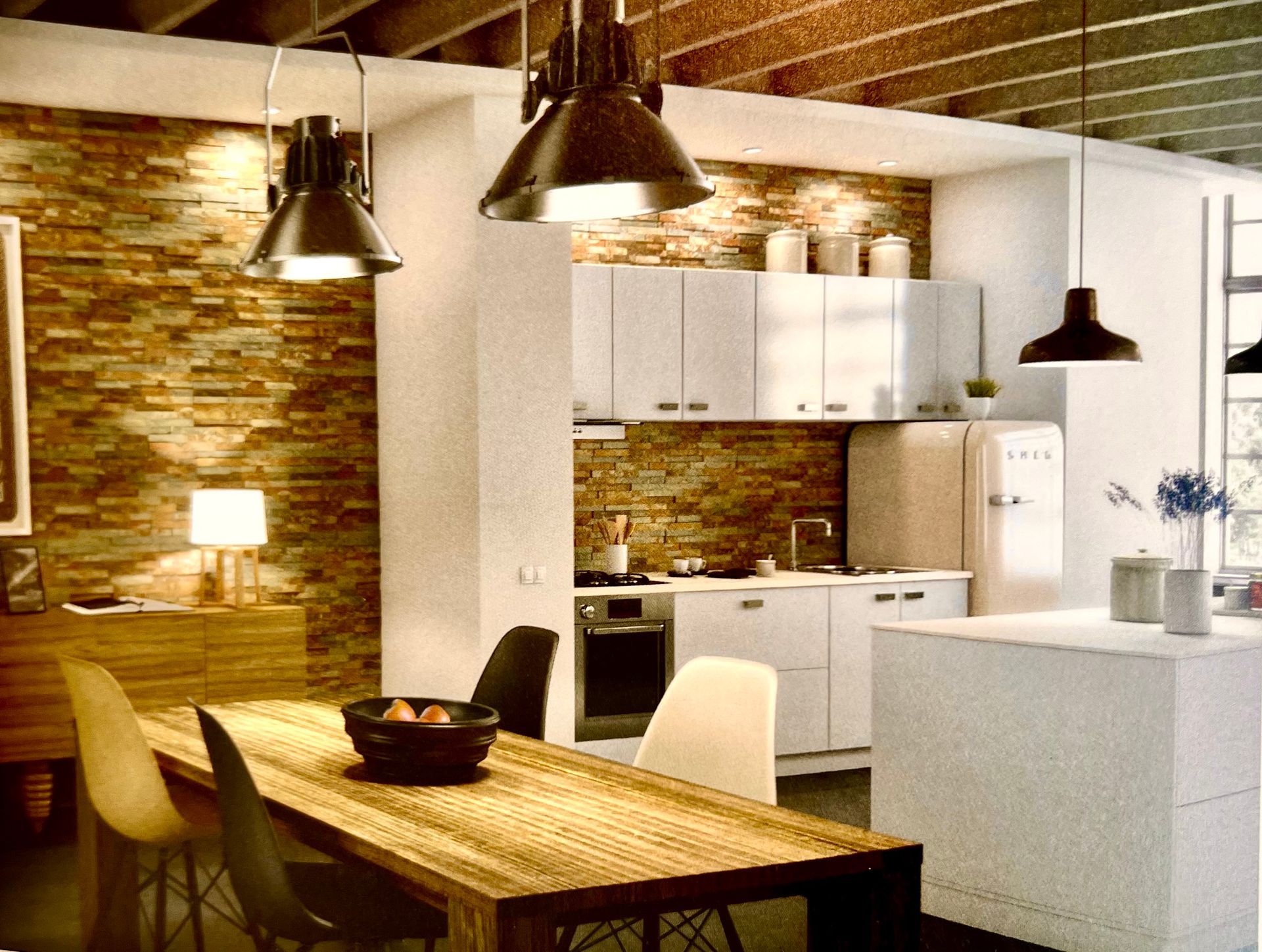 Cuisine moderne avec mur de briques, armoires blanches, table à manger en bois et luminaires suspendus industriels.