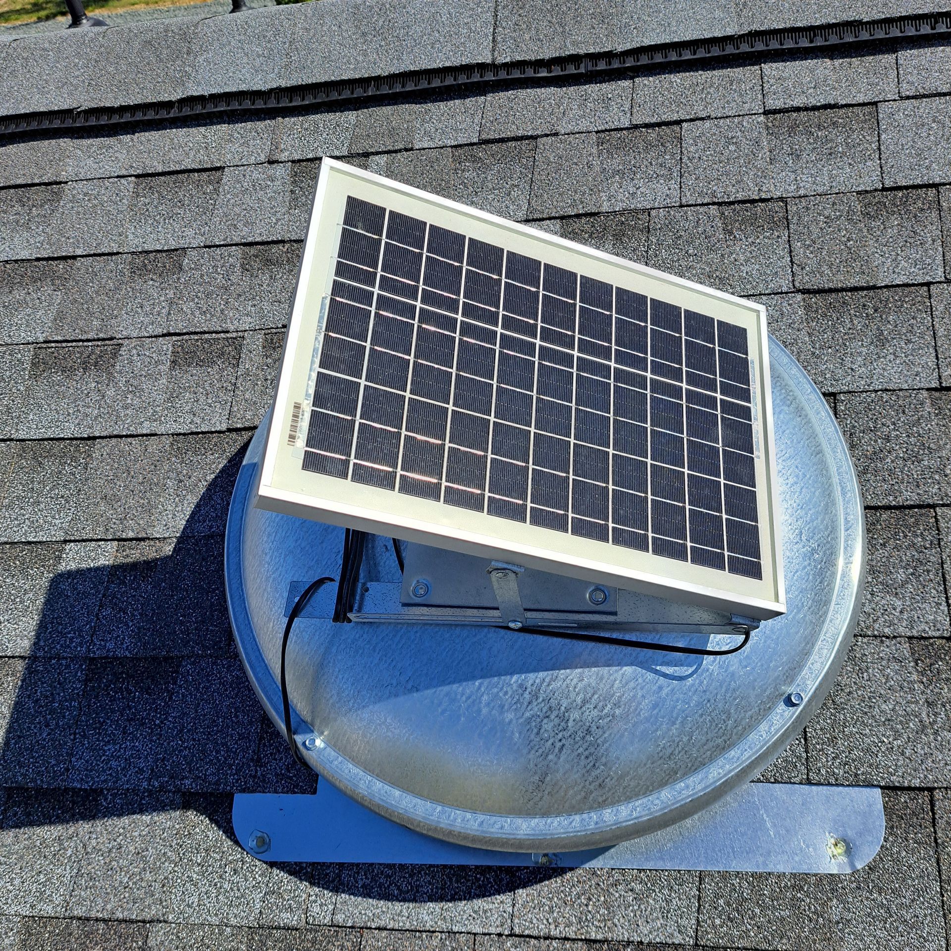 A solar panel is sitting on top of a roof fan.