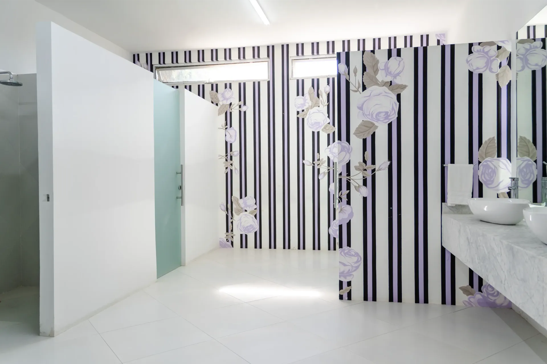 Baño moderno blanco con una pared de rayas blancas y negras y lámparas colgantes de vidrio