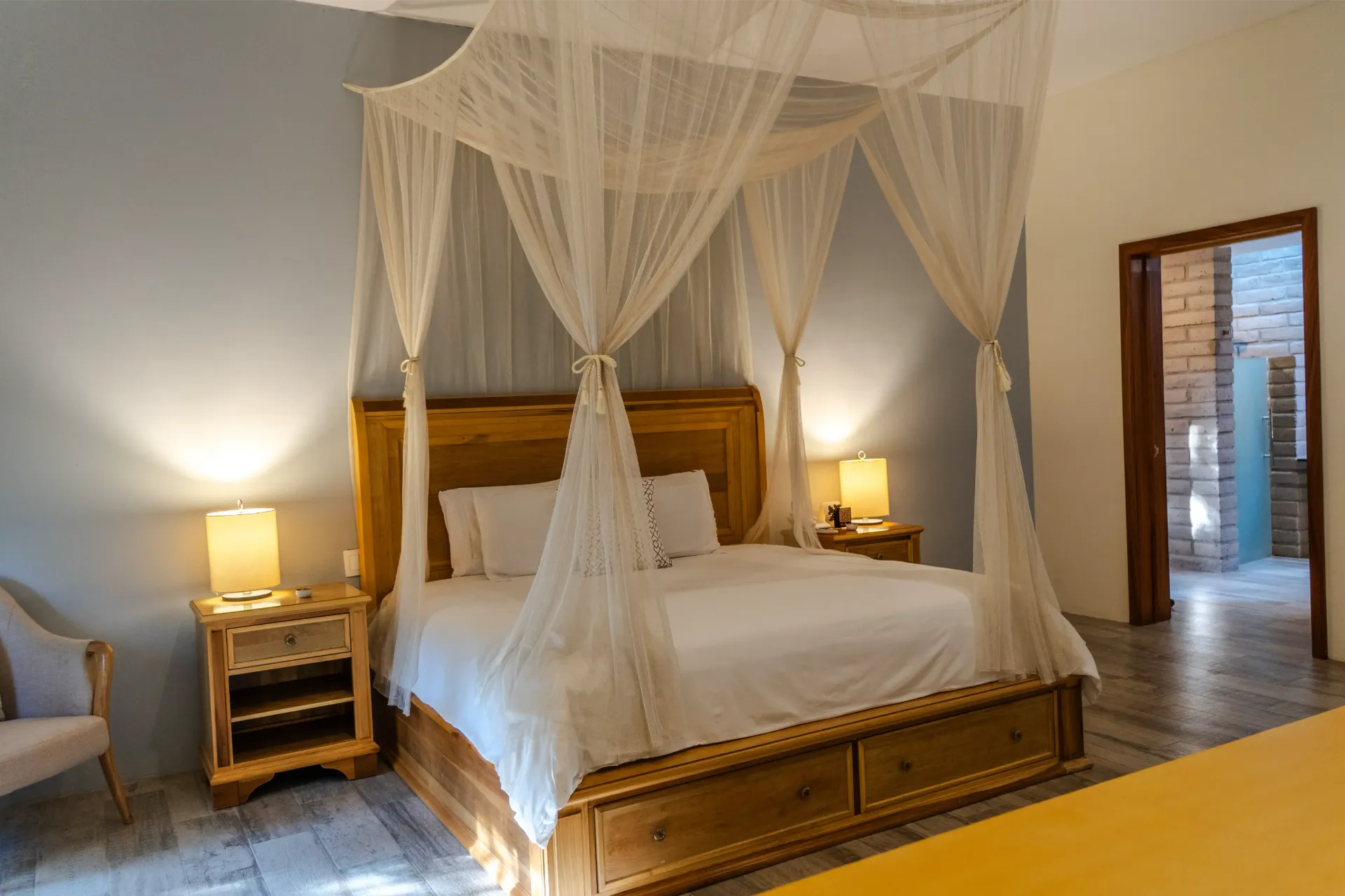 Acogedor dormitorio con cama con dosel, lámparas de noche y una puerta abierta que da a un baño alicatado