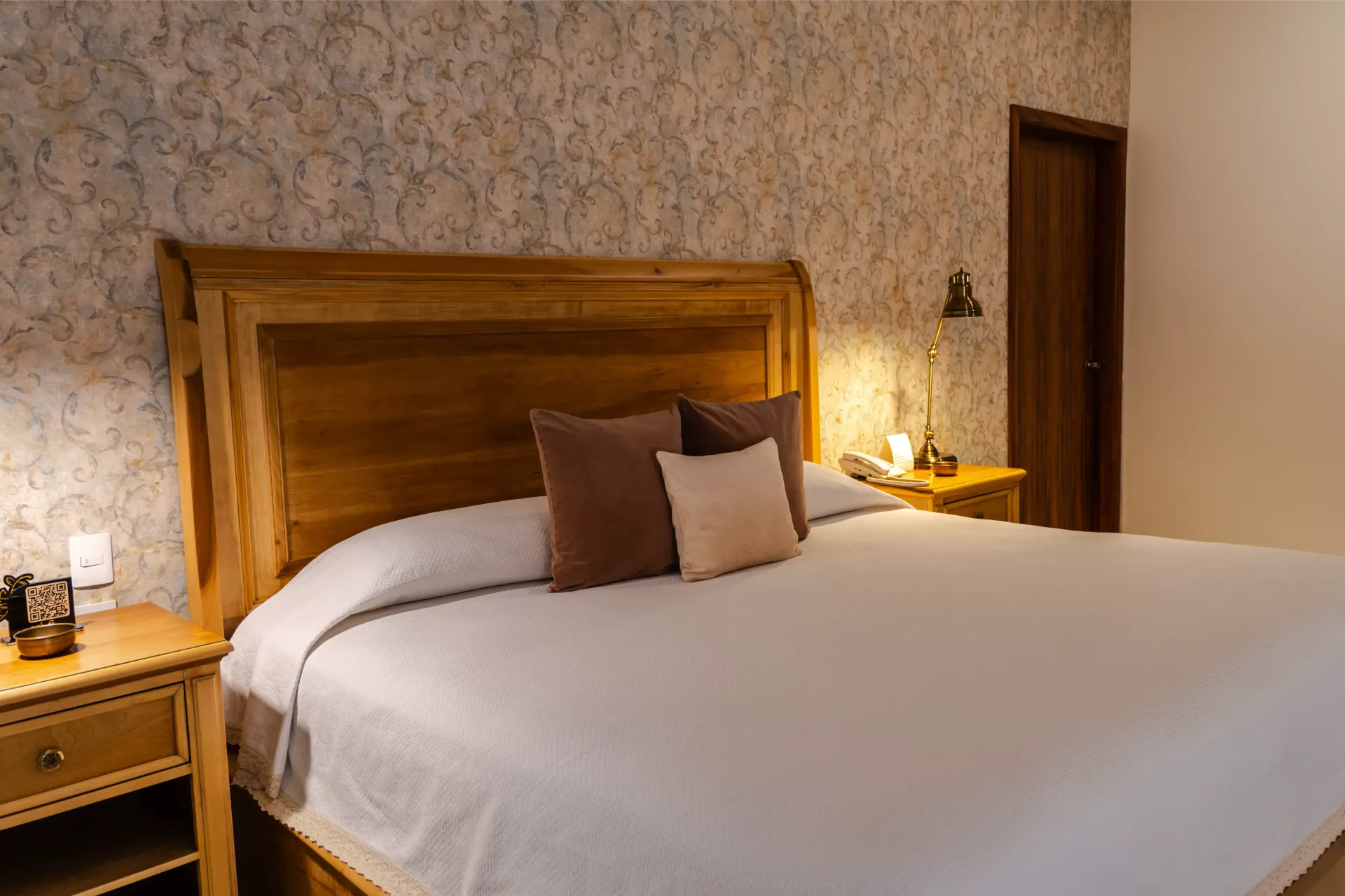 Dormitorio acogedor con cama de madera, ropa de cama blanca, lámparas de mesilla y papel pintado con textura