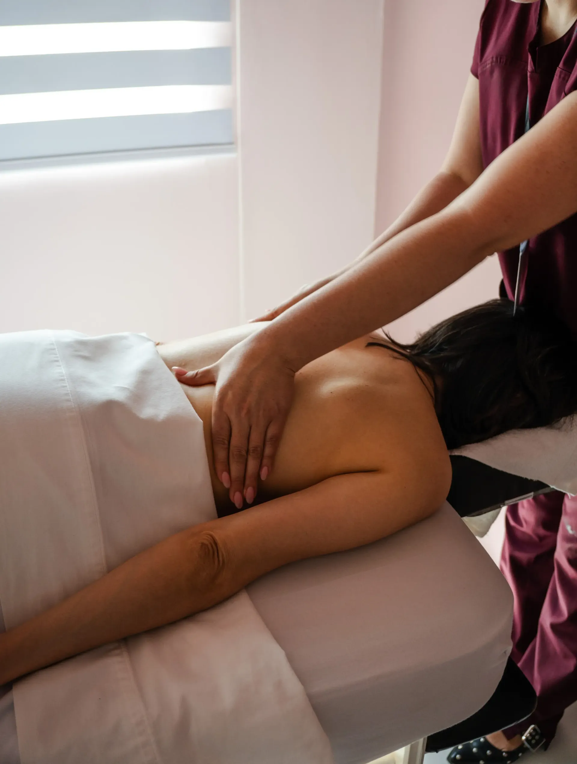 Masajista trabajando en la espalda de un cliente en una camilla de tratamiento en una sala de spa