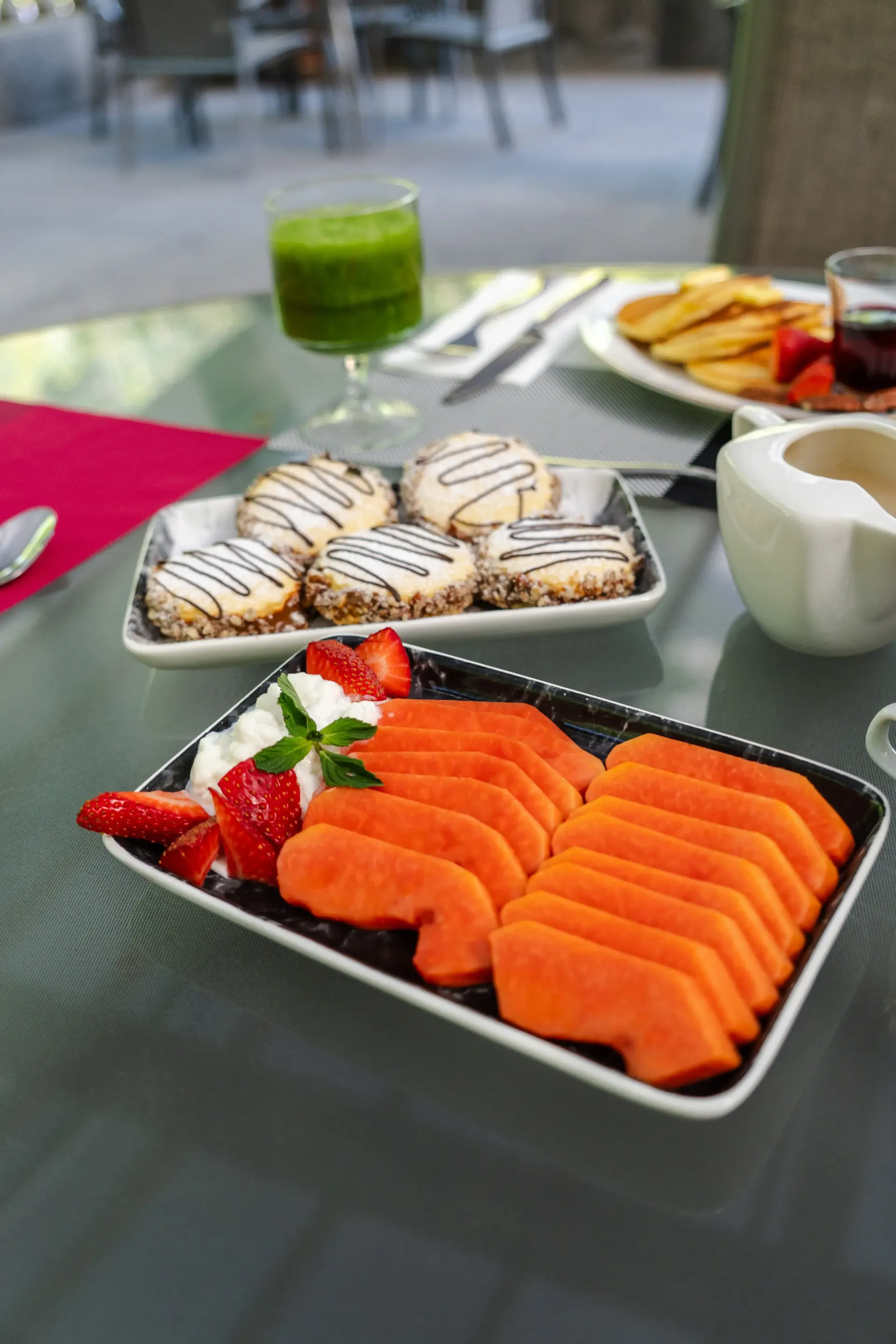 Bandeja de sushi con nigiri de salmón y rollos sobre una mesa, con bebidas y otros platos cerca