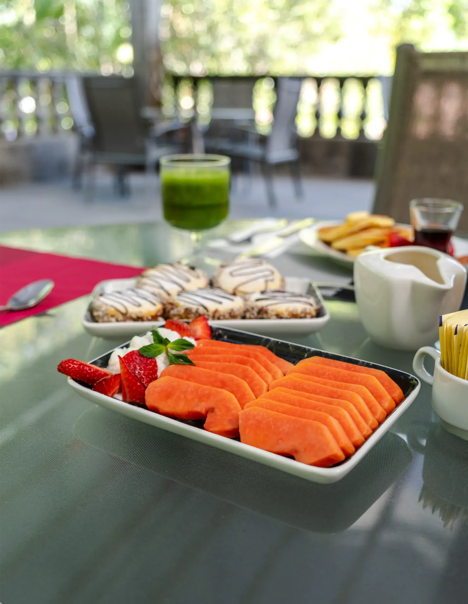 Salmón ahumado sobre una mesa en un desayuno al aire libre, con fruta, pan y una bebida verde