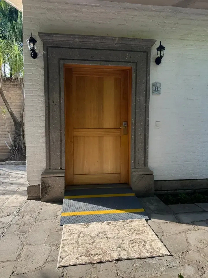 Puerta de entrada de madera con marco de piedra y una pequeña rampa de acceso