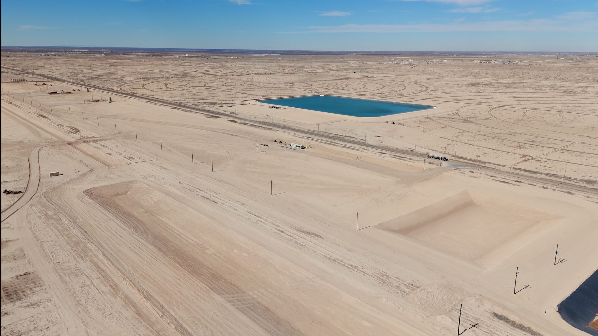 An aerial view of a desert with a small lake in the middle