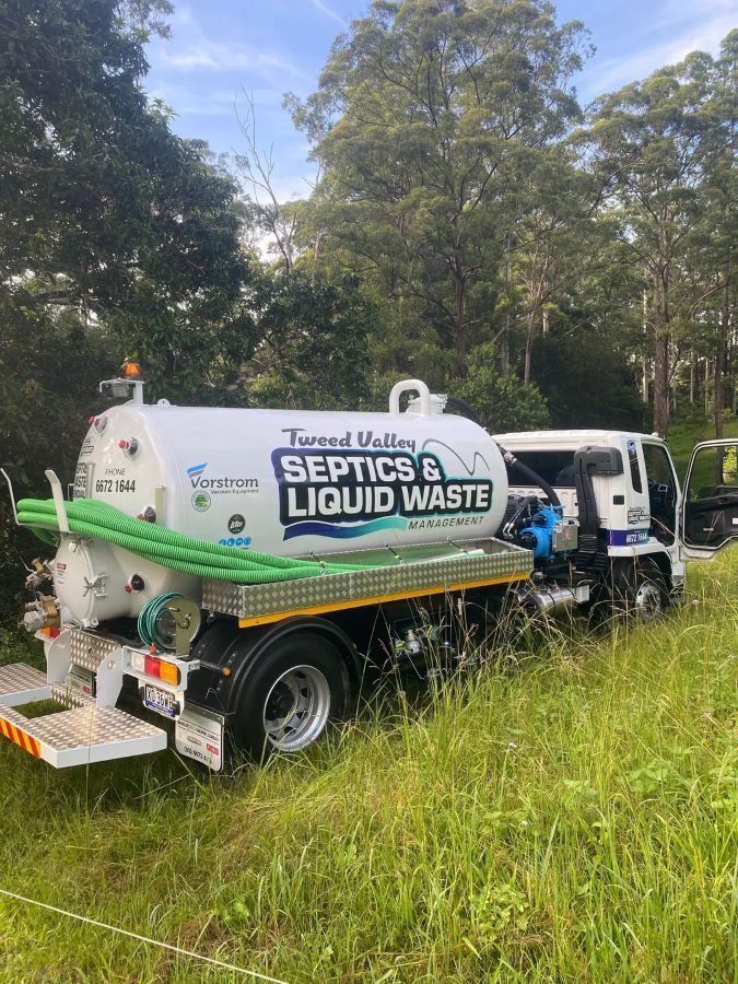 A Septic And Liquid Waste Truck Is Parked In A Grassy Field — Tweed Valley Septics & Liquid Waste Management in Cudgen, NSW