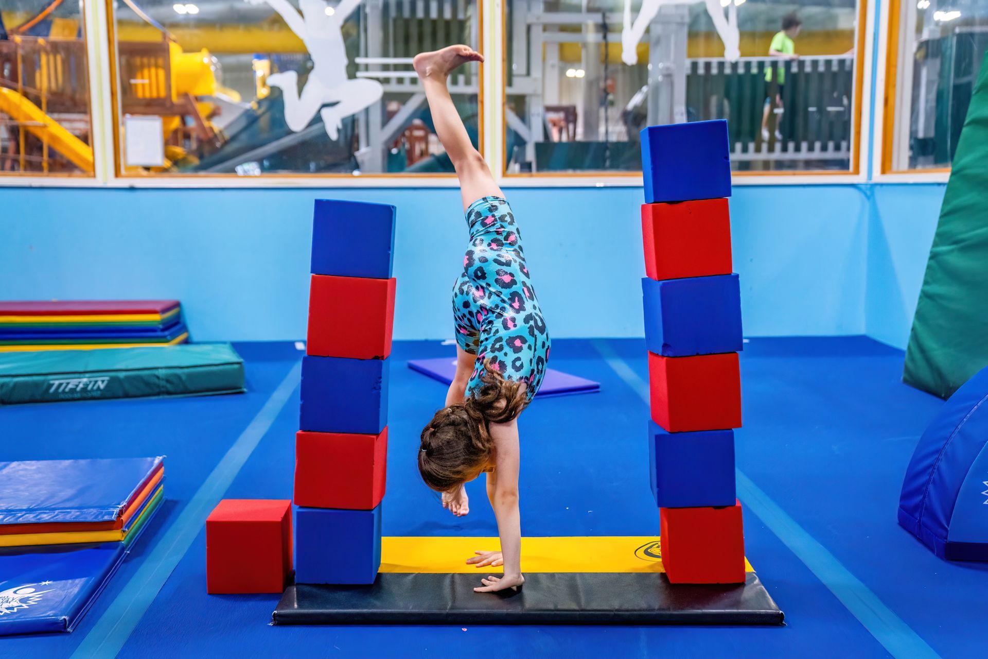 A young girl is doing a handstand in a gym.