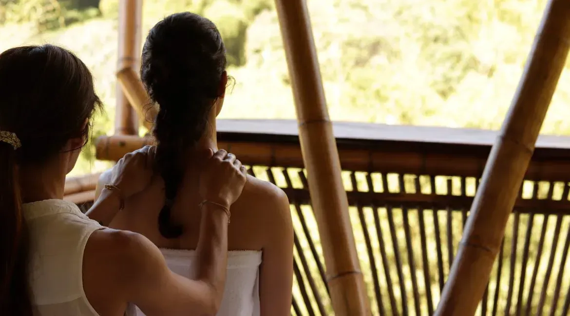 A woman is getting a massage from another woman while sitting on a balcony.