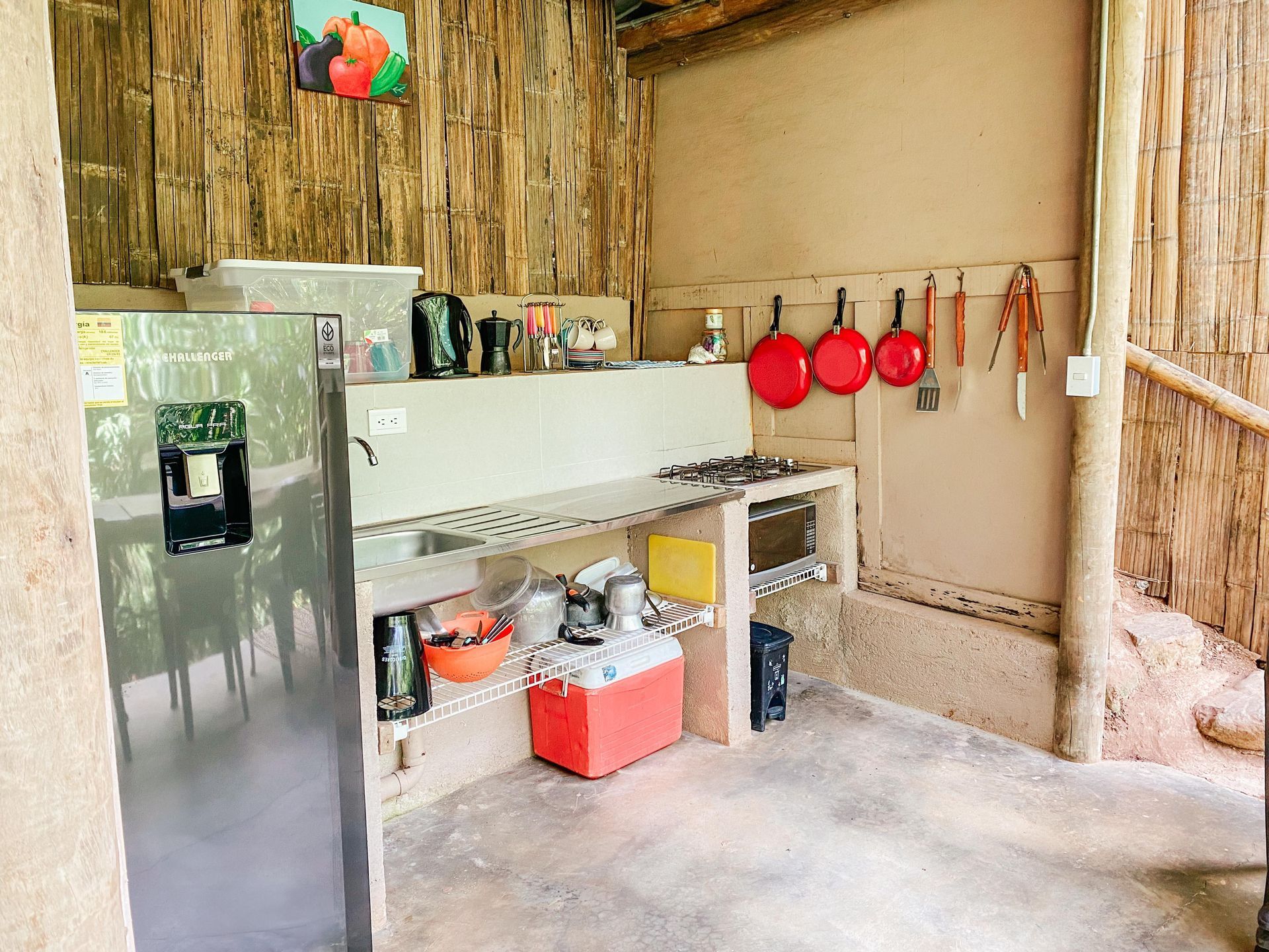 A kitchen with a refrigerator , sink , stove and pots and pans hanging on the wall.