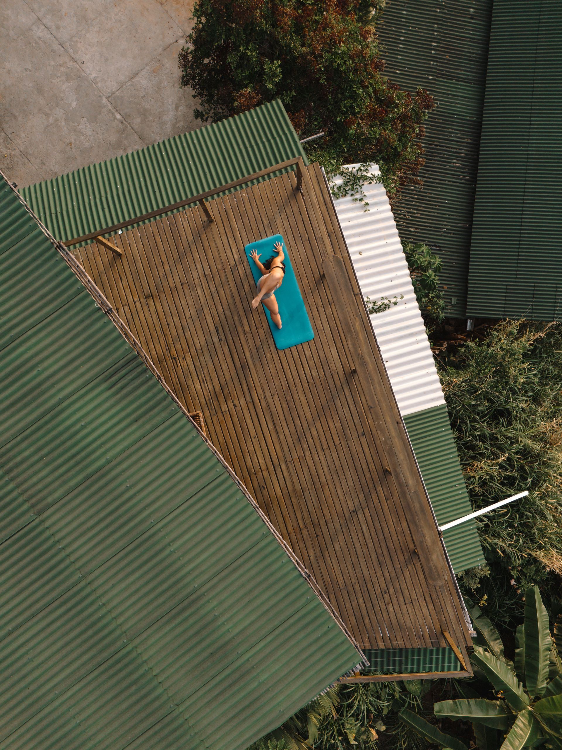 An aerial view of a person laying on a yoga mat on a deck.