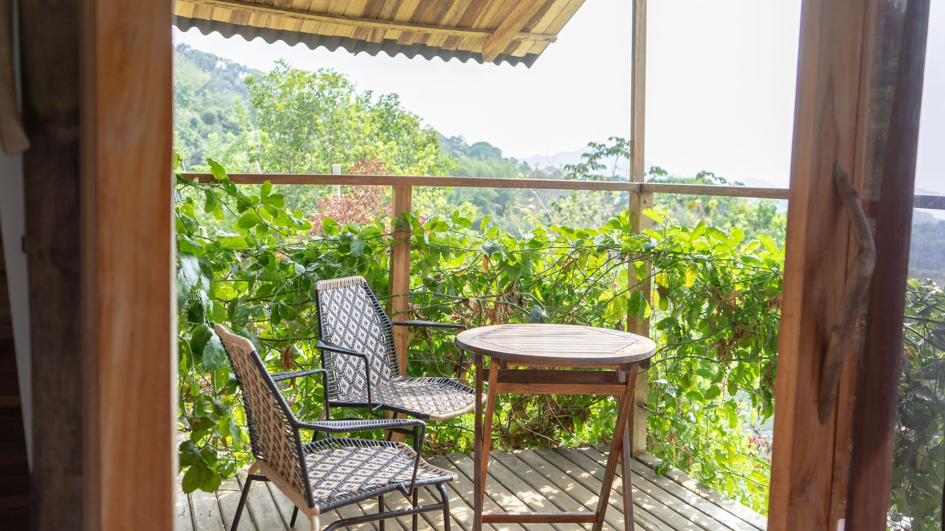 A wooden deck with a table and chairs surrounded by trees.