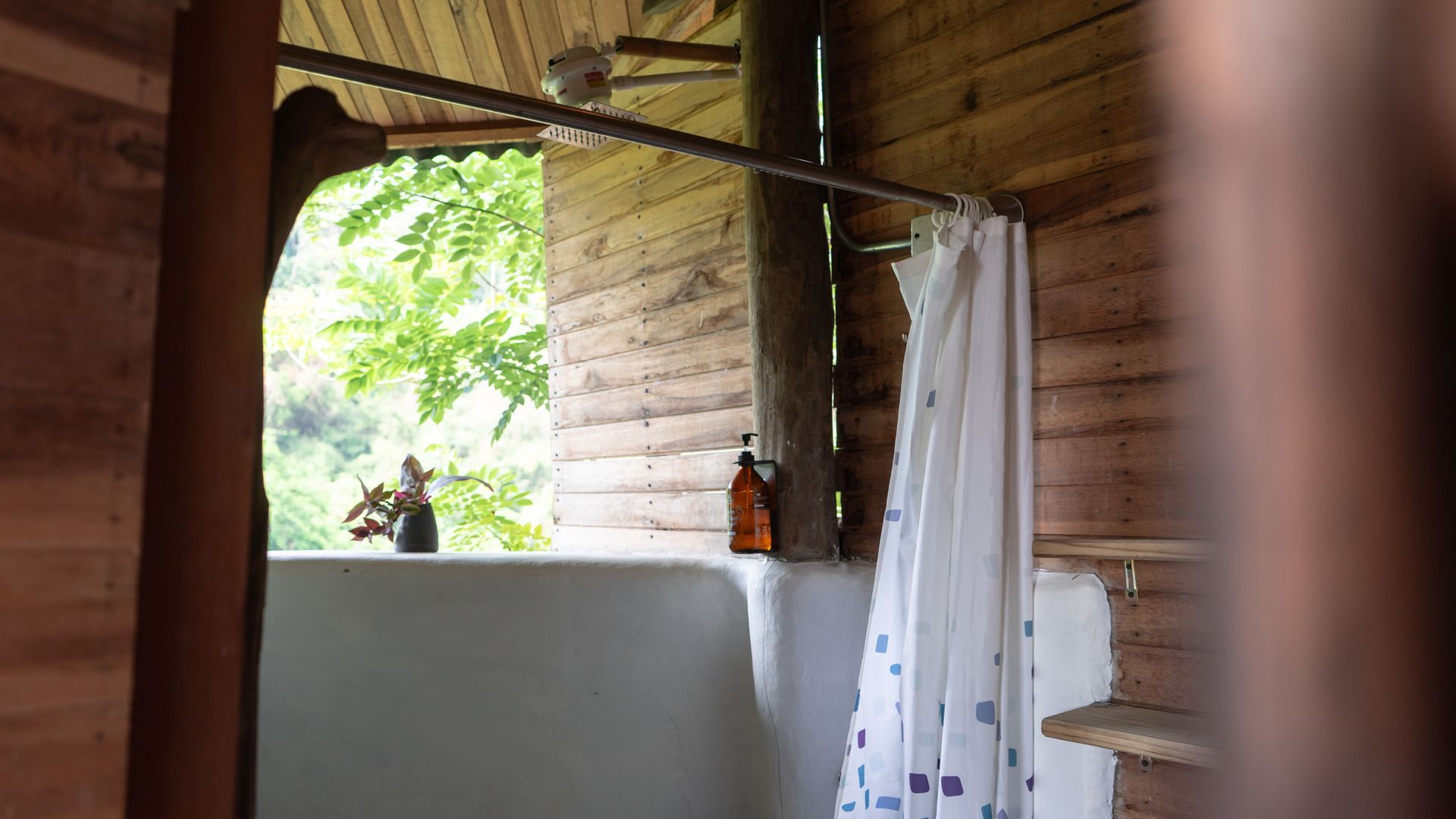 A bathroom in a log cabin with a bathtub and shower curtain.