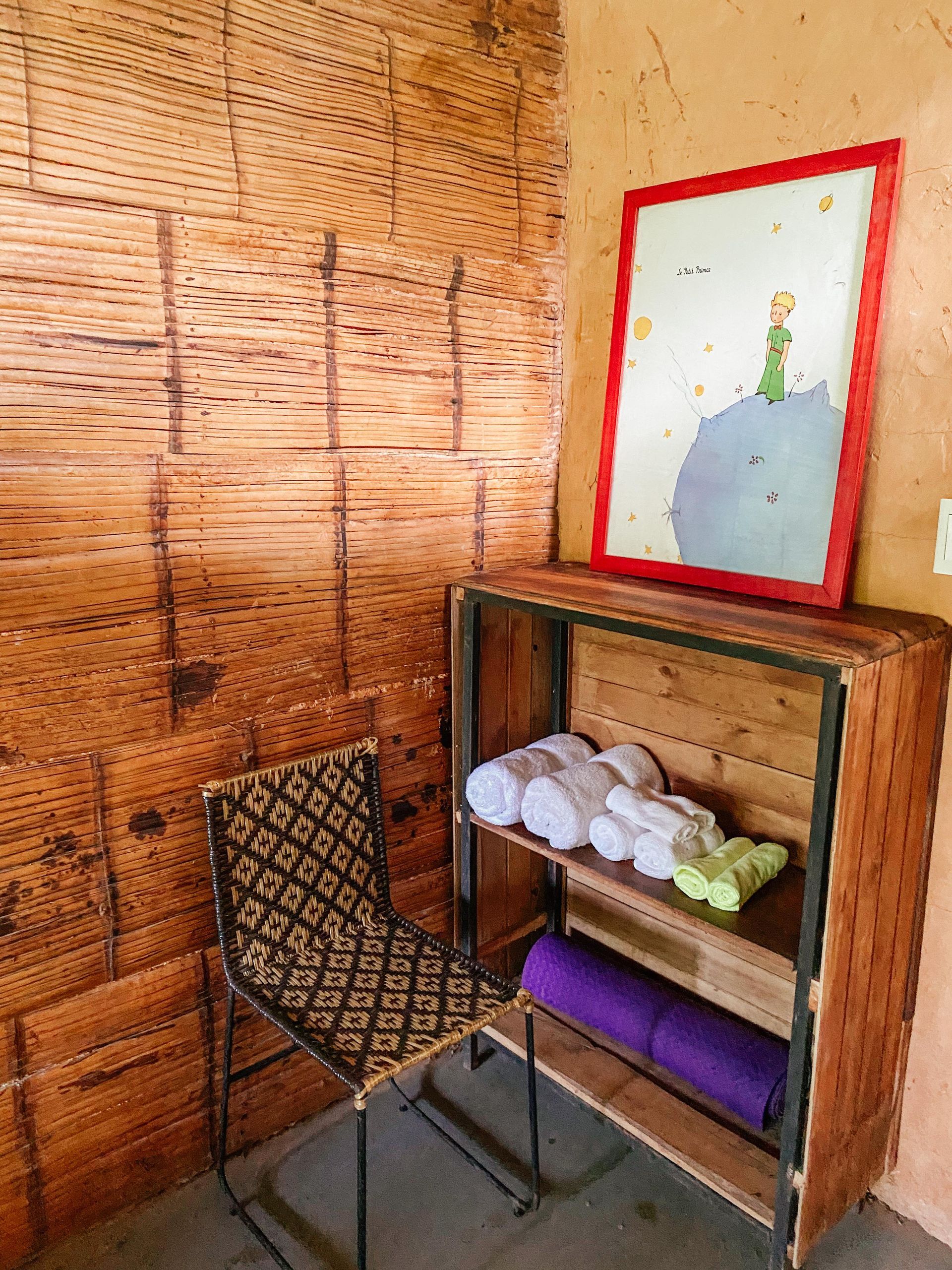 A chair is sitting next to a wooden shelf with towels on it.