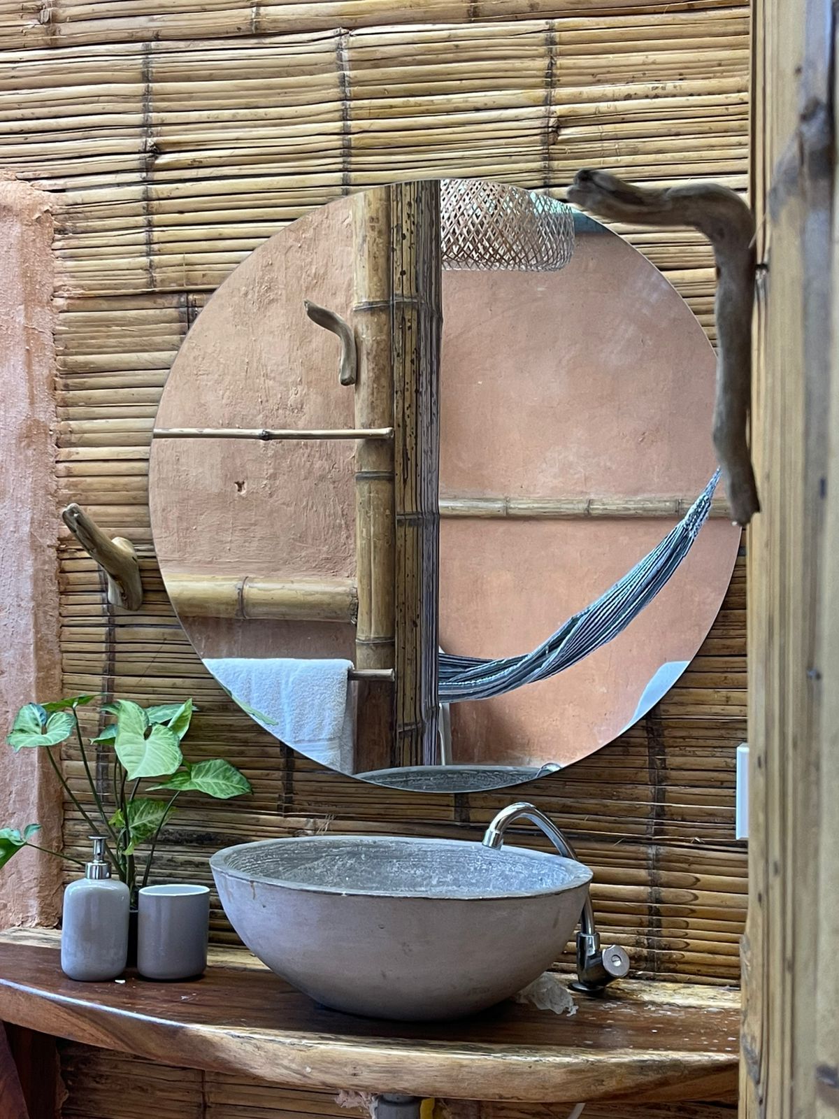 A bathroom with a sink , mirror and hammock.