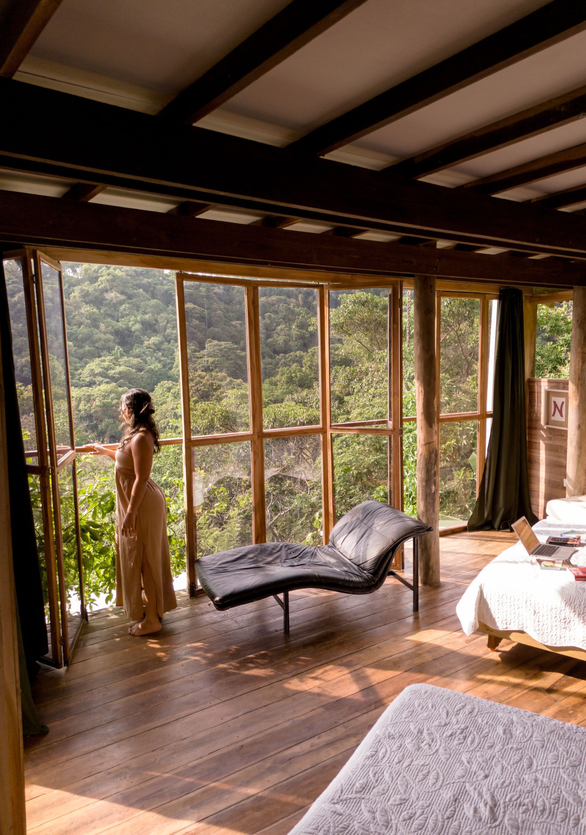 A woman is standing in front of a large window looking out.