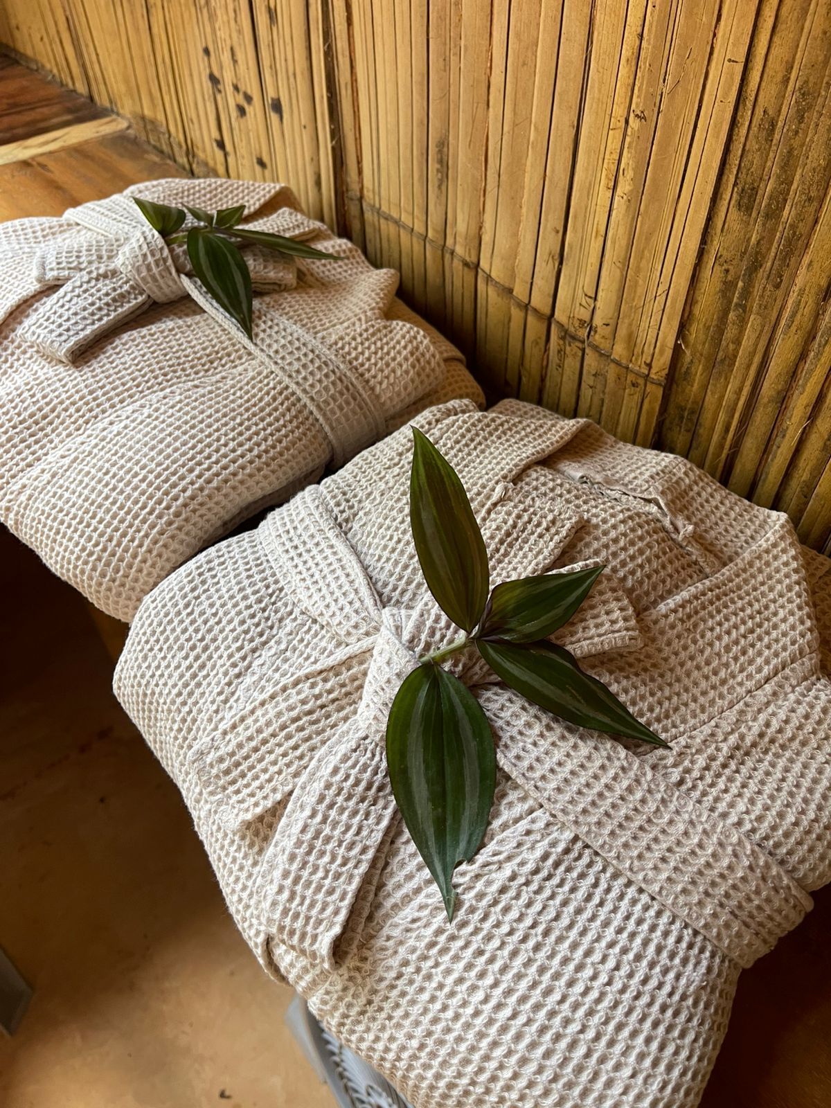 Two bathrobes with leaves on them are sitting on a wooden bench.