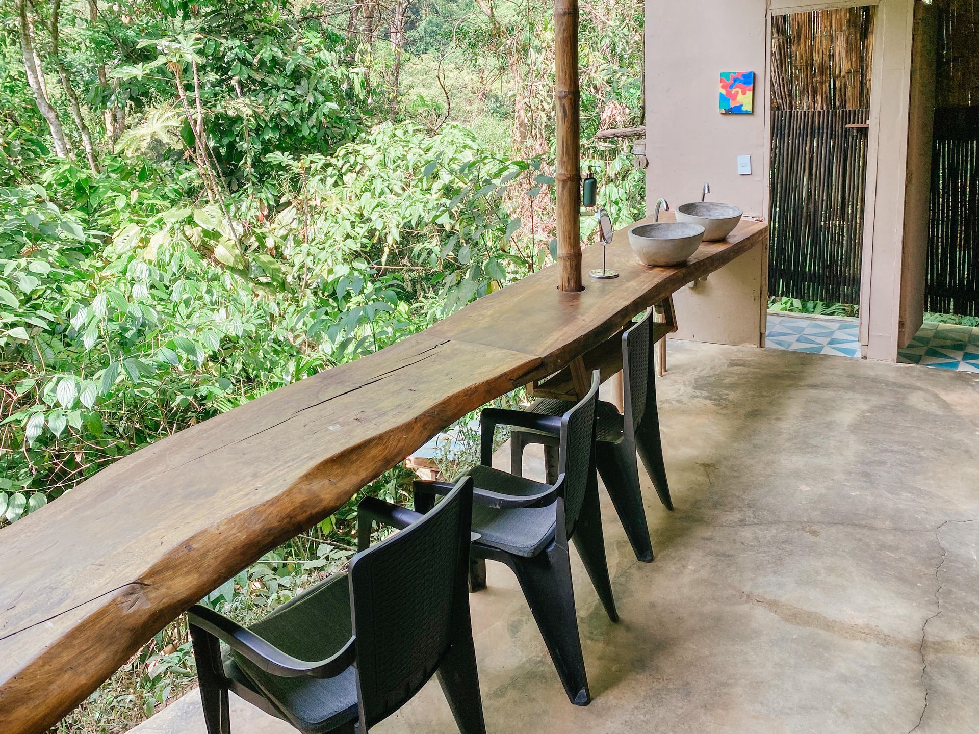 A wooden table and chairs on a balcony overlooking a forest.
