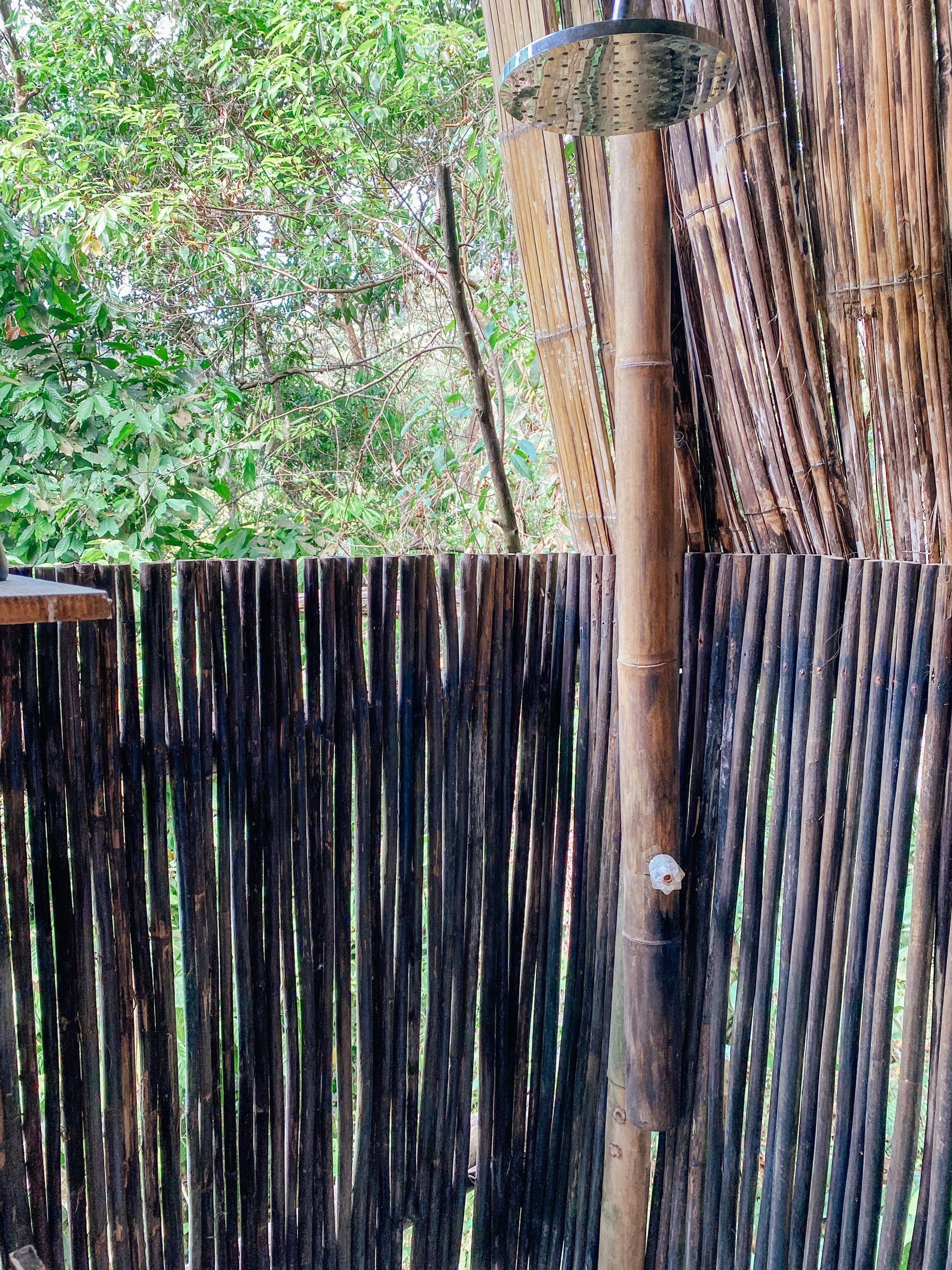 A wooden fence with a shower attached to it.